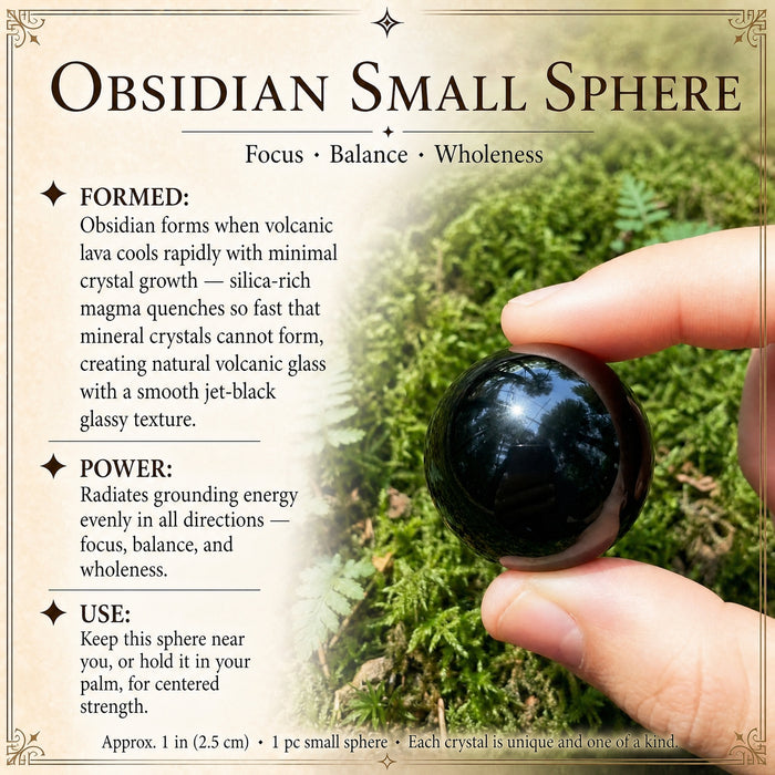 The small obsidian sphere pinched between thumb and finger over moss