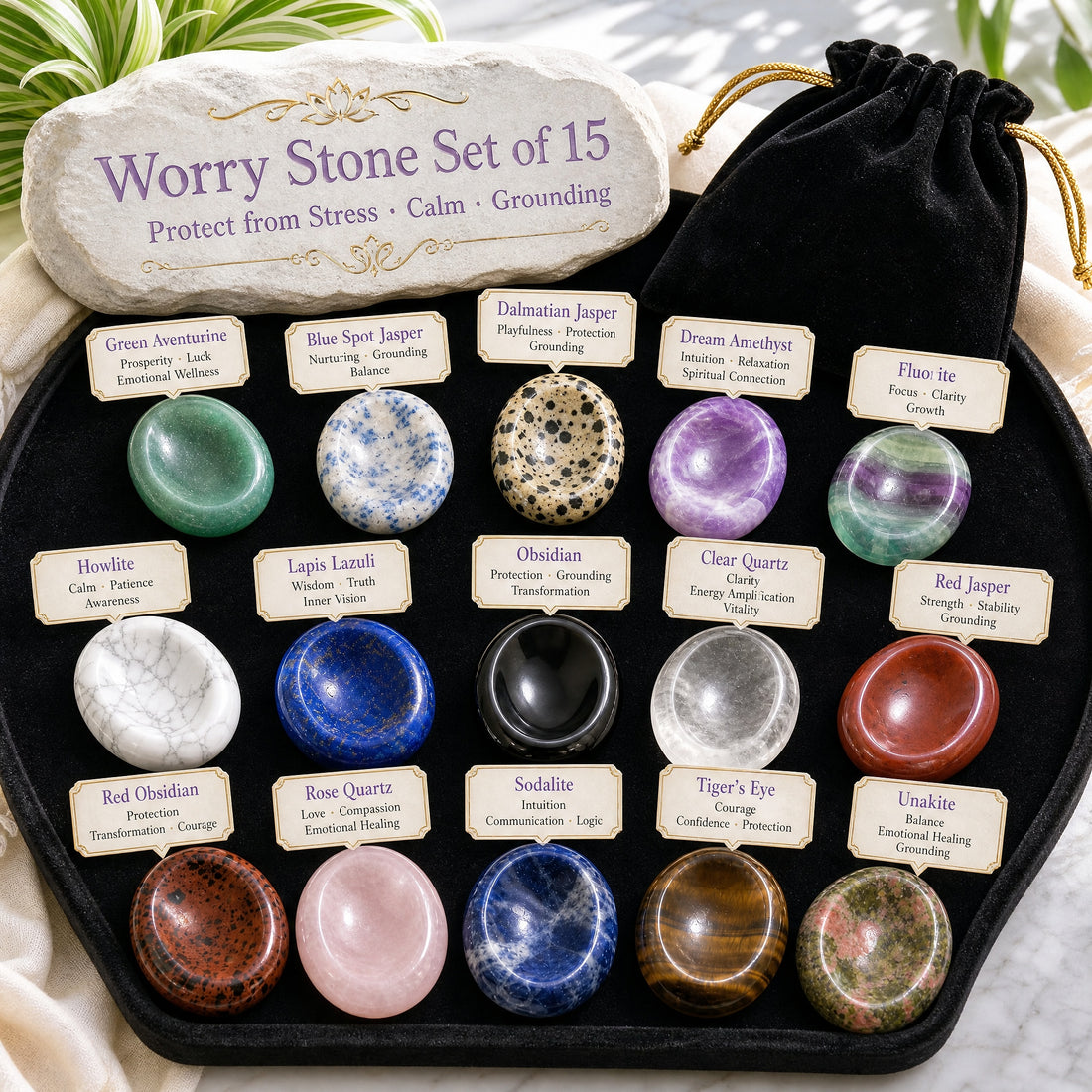 All fifteen worry stones laid out in three rows on a black velvet tray, each with a name card, beside a black velvet drawstring pouch