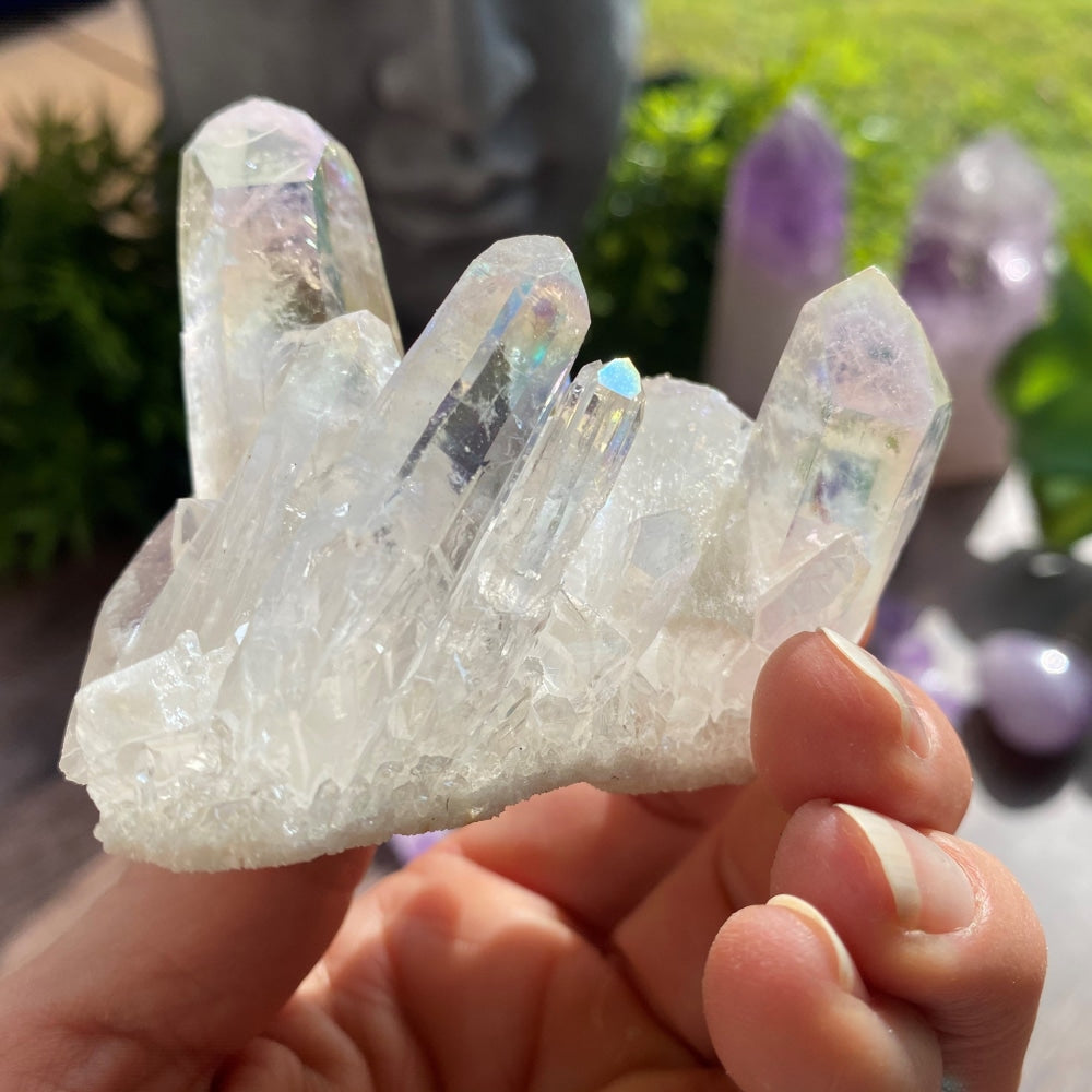 A hand holding the Angel Aura Quartz cluster