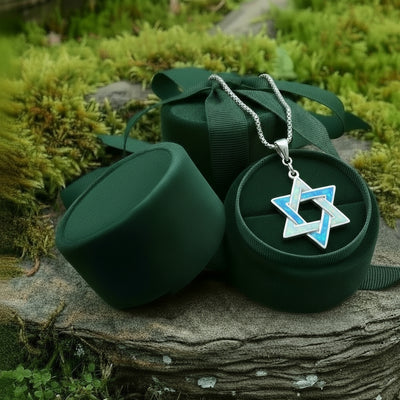 The opal Star of David pendant resting in an open round green velvet jewelry box on a mossy stone