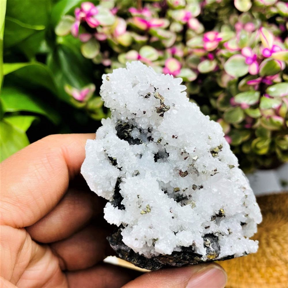 Close view of the white quartz cluster held in a hand, with small golden pyrite crystals scattered across it